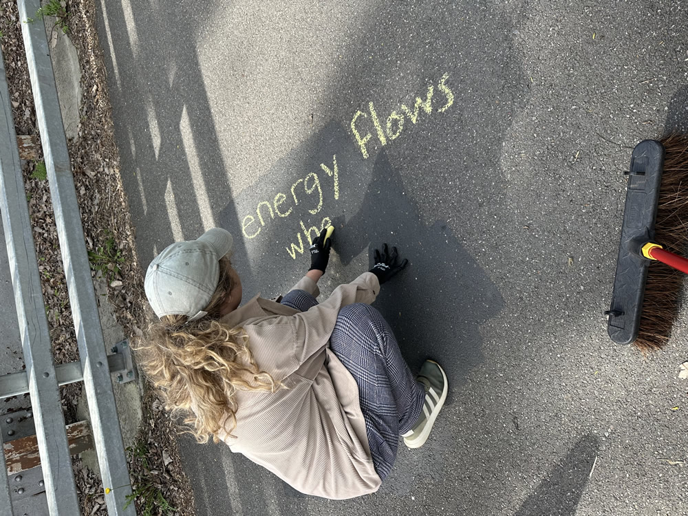 Person using sidewalk chalk to write an inspirational message along a trail