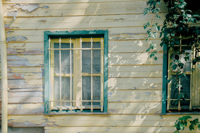 Photo of a gloved hand holding a vial marked "Lead (PB) - Test" with a painted window sill in the background