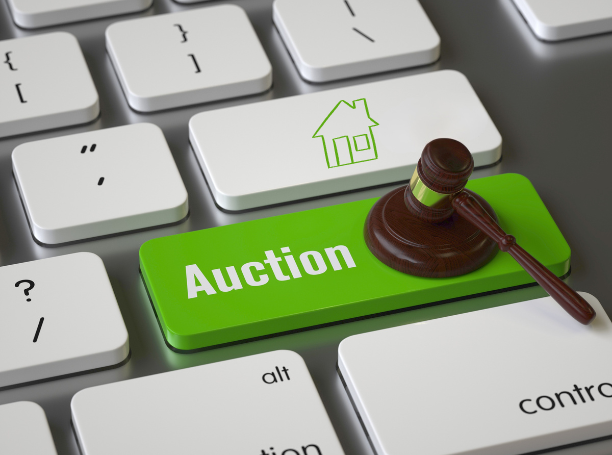 Photo of computer keyboard with a green "Auction" button in place of the enter key, and a wooden gavel clicking the key