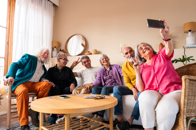 Photo of smiling seniors sitting on a sofa taking a selfie