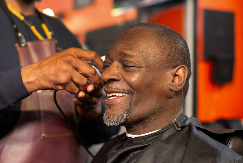 Photo of smiling man getting his hair trimmed.