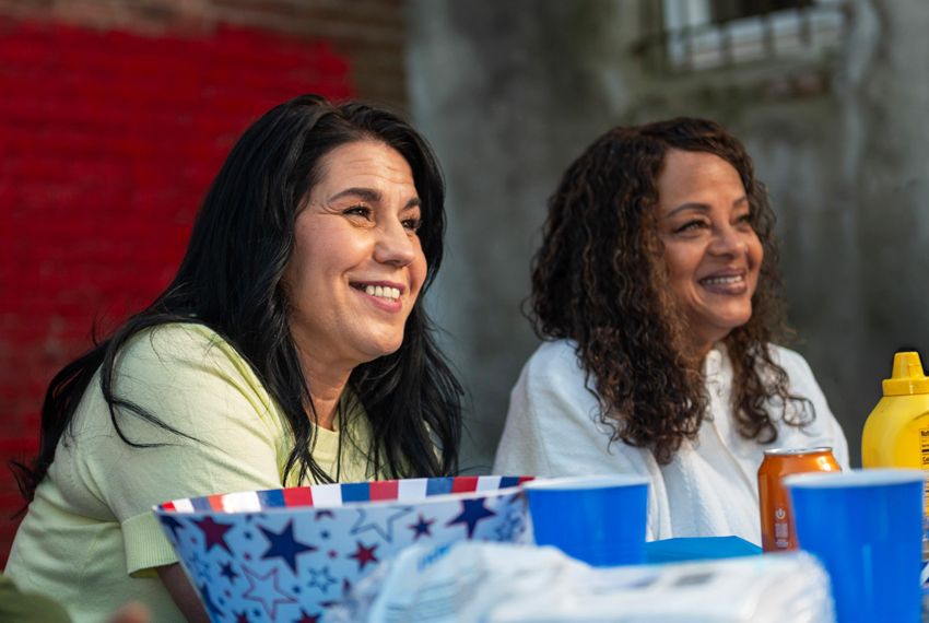 Photo of smiling people seated at a picnic table.